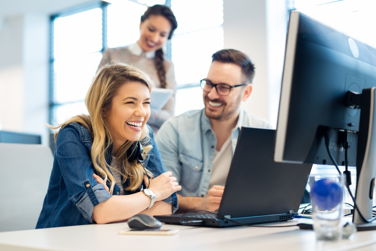 Business owners smiling at the computer after getting a custom software solution from Custom Code